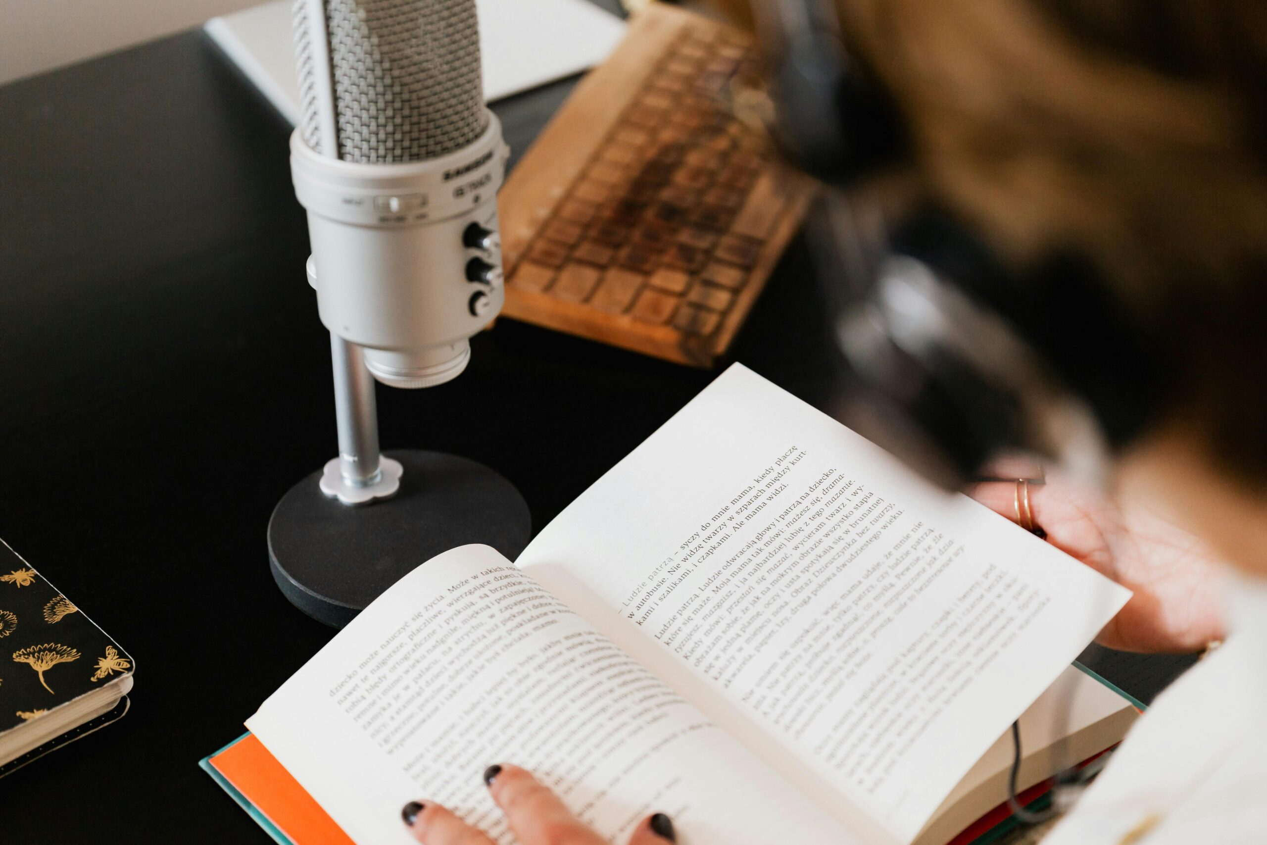 Close-up of a person reading with a microphone on a desk.